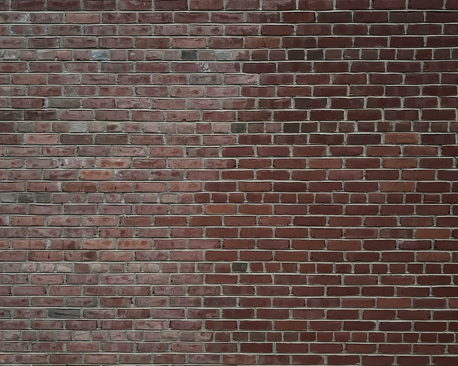 Brick wall half cleaned: the left side dull and hazy with residue, the right side clean with even color